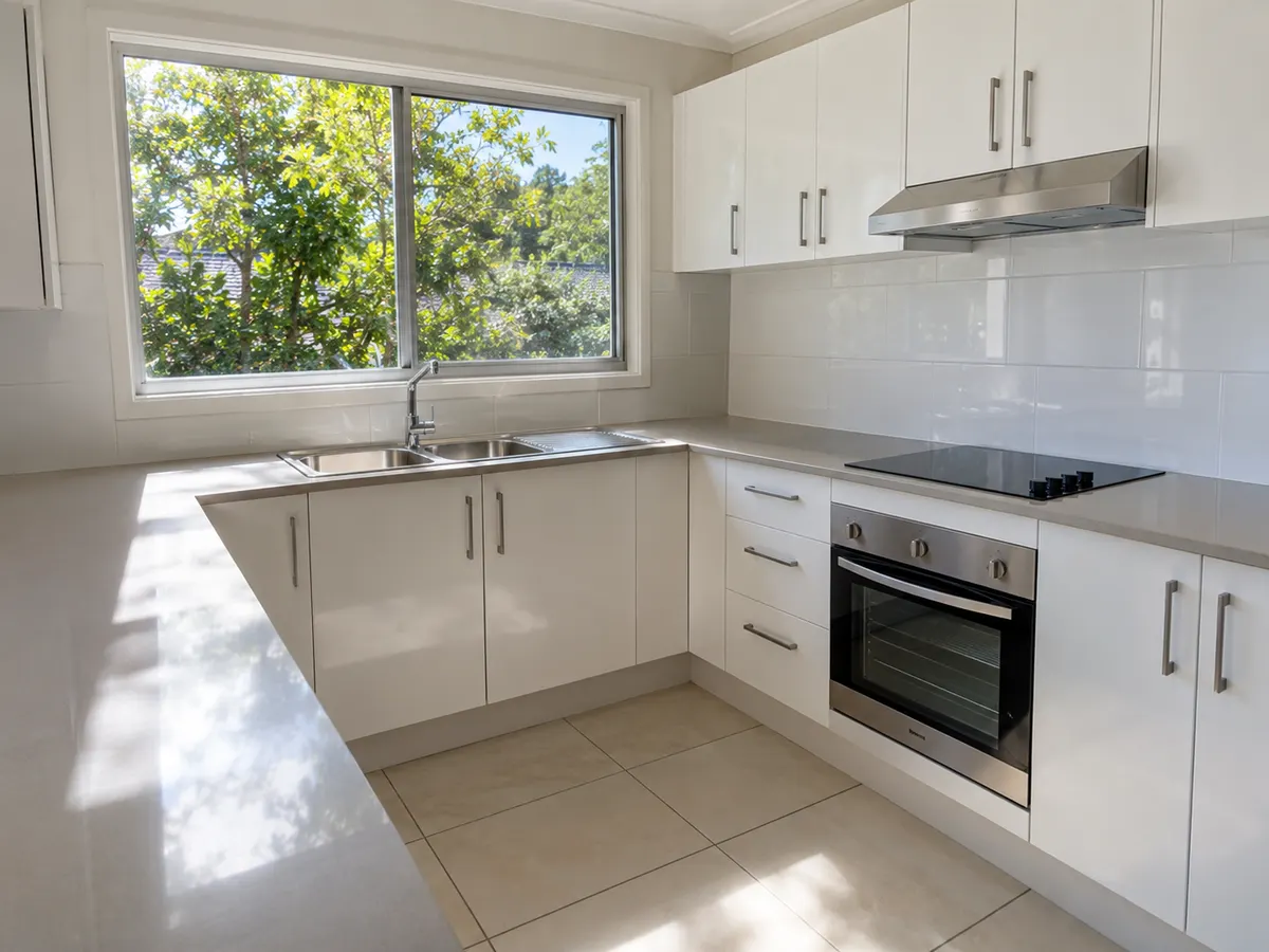 Clean kitchen with clear benchtops, sink and oven